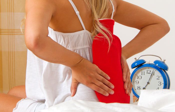 Applying a heat pack to alleviate lower back pain, demonstrating the use of heat therapy to relax muscles and reduce pain.