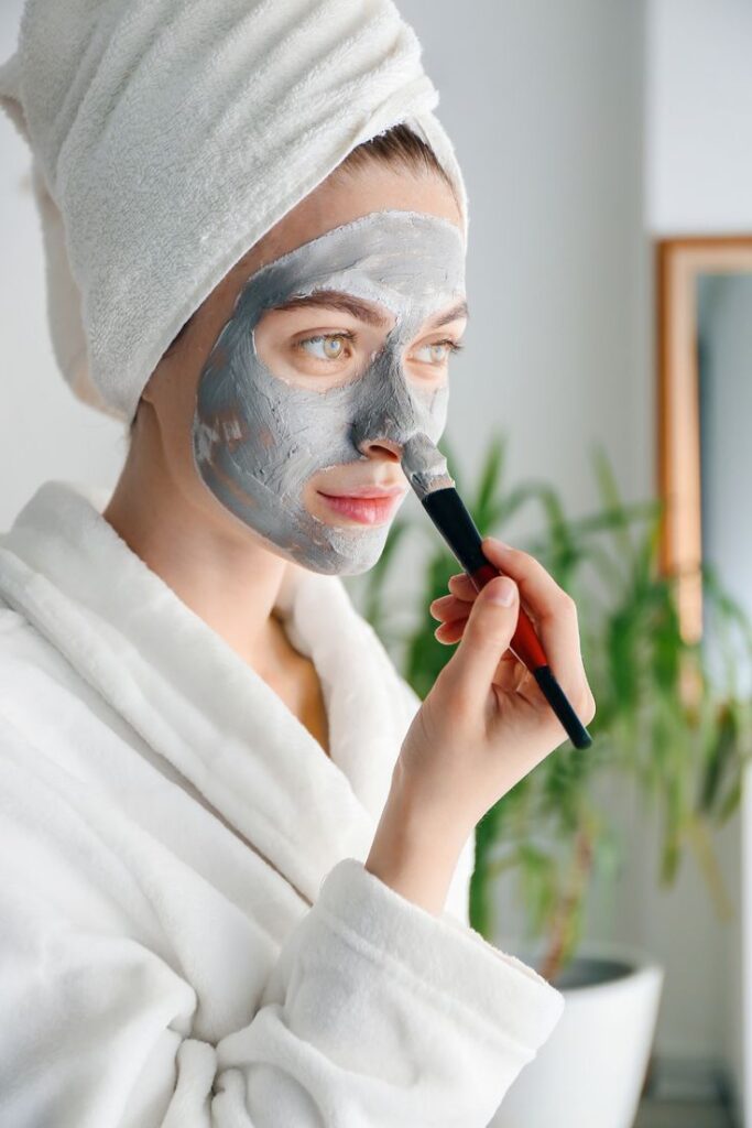 Skin Care, a woman applying moisturizer to her face, showcasing a daily skin care routine. The image emphasizes the importance of maintaining healthy skin through proper hydration and care.