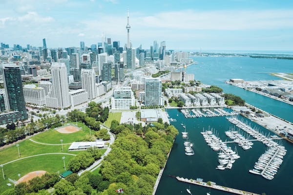 Family enjoying a summer vacation in Toronto, Canada, with a backdrop of the iconic CN Tower and vibrant city skyline.