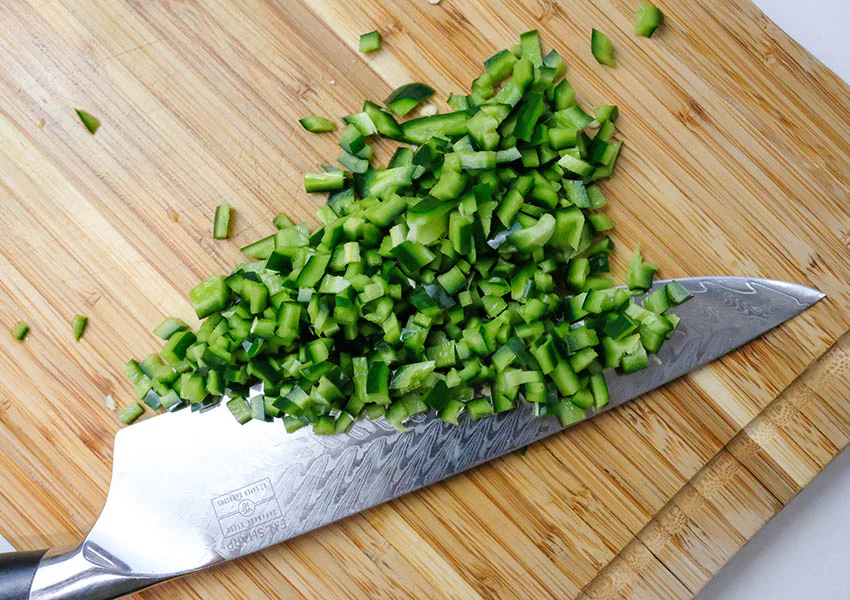 Image showing freshly chopped vegetables, including lettuce, tomatoes, cucumbers, and onions, laid out on a cutting board. These vibrant veggies are being prepared as key ingredients for a Chicken Salad Sandwich, adding crunch and flavor to the recipe