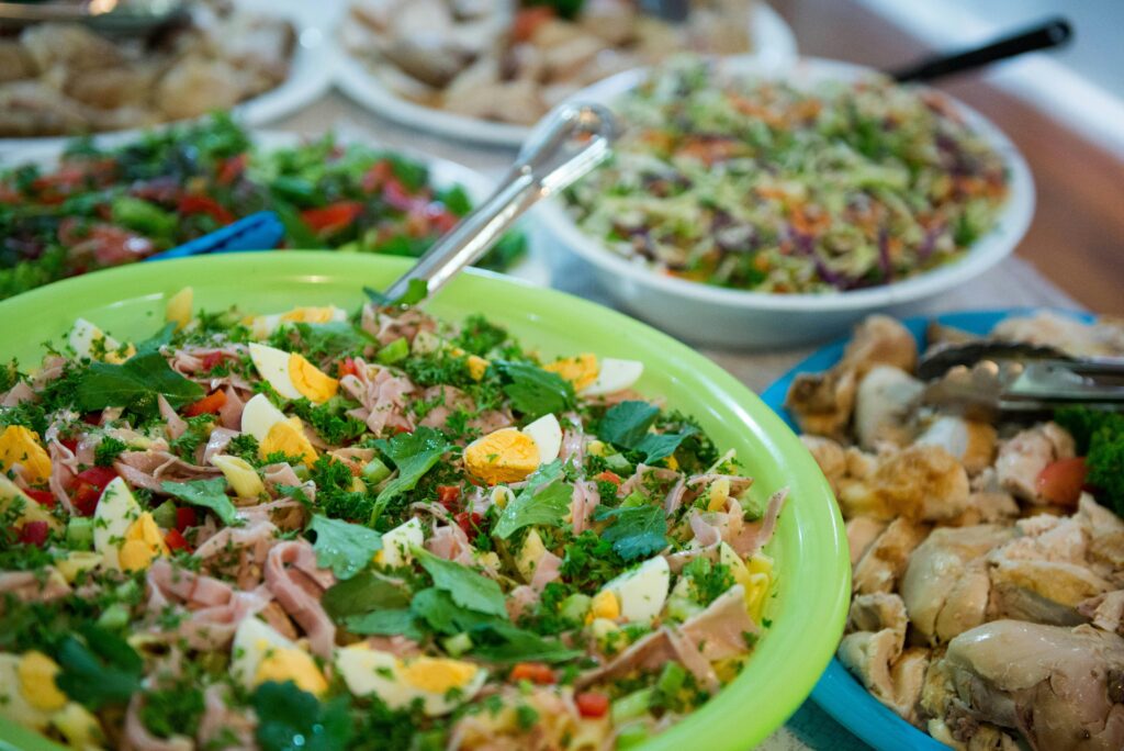 A variety of fresh ingredients for a Chicken Salad Sandwich laid out on a wooden cutting board, including diced cooked chicken, celery, red onion, mayonnaise, and fresh lettuce. A bowl of salad mixture and slices of whole-grain bread are ready to assemble a delicious Chicken Salad Sandwich.