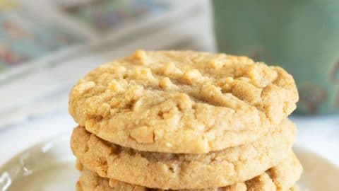 A close-up image of gluten-free peanut butter cookies arranged neatly on a baking sheet. The cookies have a golden-brown color with a classic crisscross fork pattern on top, showcasing their rich, creamy texture. The slightly crumbly edges and soft centers make them look delicious and inviting. Perfectly baked, these peanut butter cookies have a smooth, shiny surface, reflecting the natural oils from the peanut butter, making them an ideal gluten-free treat for anyone craving a sweet and nutty snack.