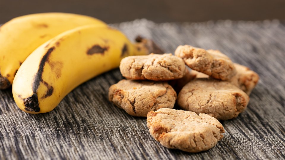 A plate of freshly baked peanut butter cookies with slices of ripe banana, showing the golden-brown texture and soft, chewy centers. The cookies are rich in peanut butter flavor, combined with the sweetness of bananas, creating a delicious treat perfect for any snack or dessert time.