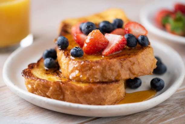 "Deliciously golden-brown slices of Perfect Fluffy French Toast, topped with a dusting of powdered sugar, fresh berries, and a drizzle of maple syrup, served on a rustic wooden plate. The toast is thick and airy, showcasing its perfect fluffy texture, inviting you to indulge in this classic breakfast treat.