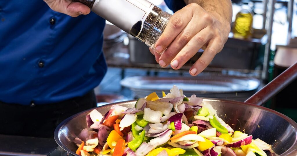 A close-up of a freshly made Chicken Salad Sandwich, showcasing tender chunks of chicken mixed with creamy mayonnaise, fresh herbs, and crunchy vegetables. The sandwich is being tasted to adjust the seasoning, ensuring the perfect balance of flavors before serving.