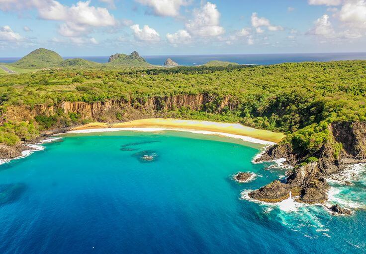 A breathtaking view of Baia do Sancho, Fernando de Noronha, Brazil, featuring golden sands, lush green cliffs, and crystal-clear turquoise waters, showcasing one of the Best Beaches in the World.